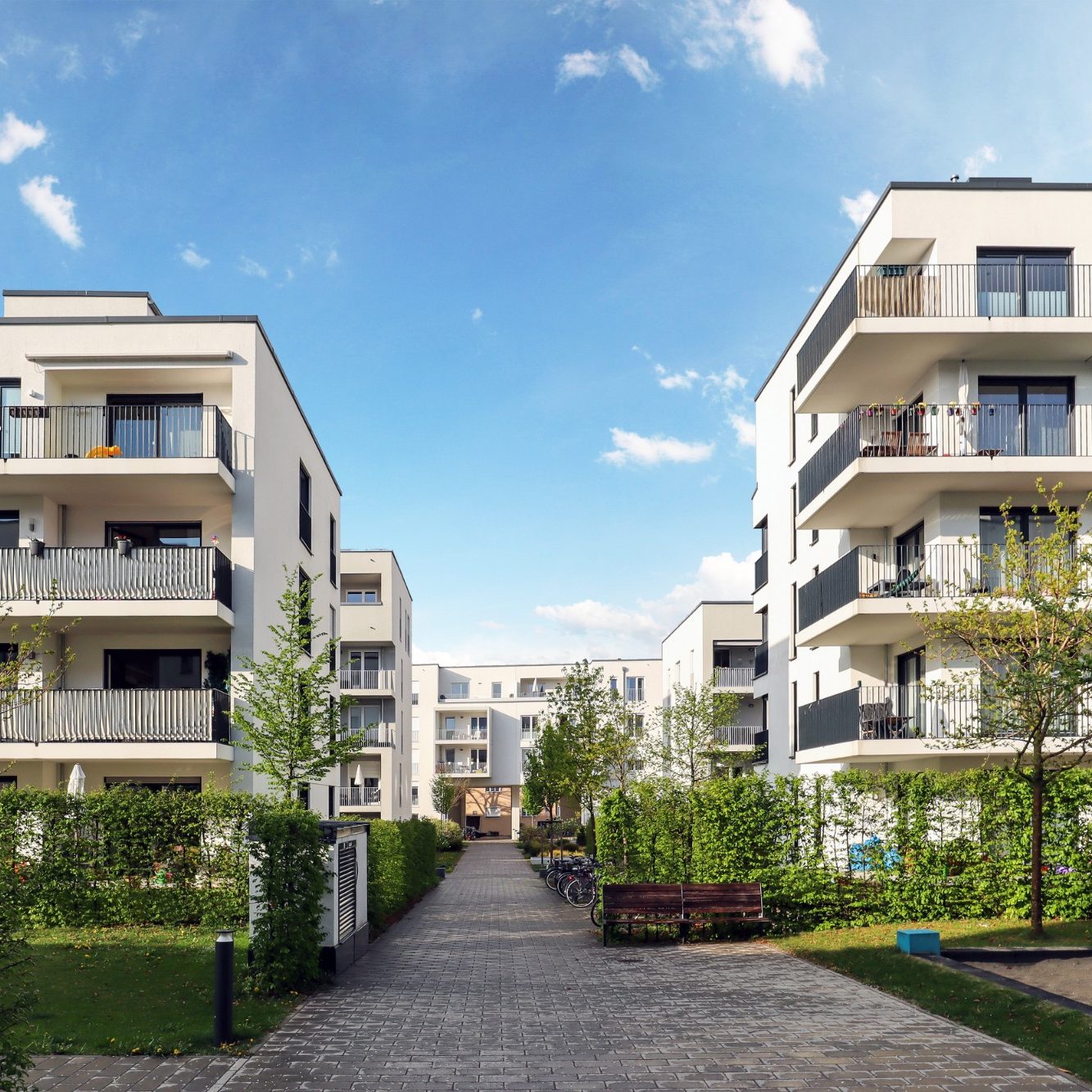 Moderne Wohngebäude mit Balkonen und Garten in einer ruhigen Stadtumgebung.